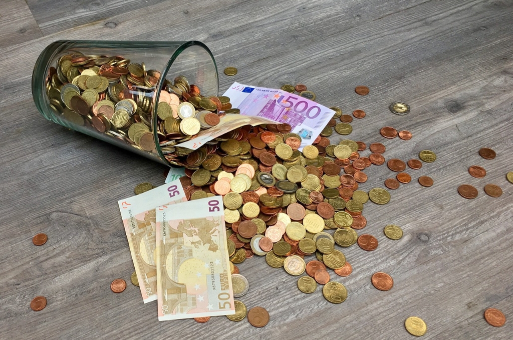 Bargeld abschaffen: Umgekipptes Glas mit Münzgeld und Scheinen