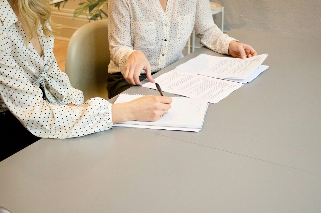 Rürup-Rente: zwei Frauen sitzen am Schreibtisch und unterzeichnen einen vertrag