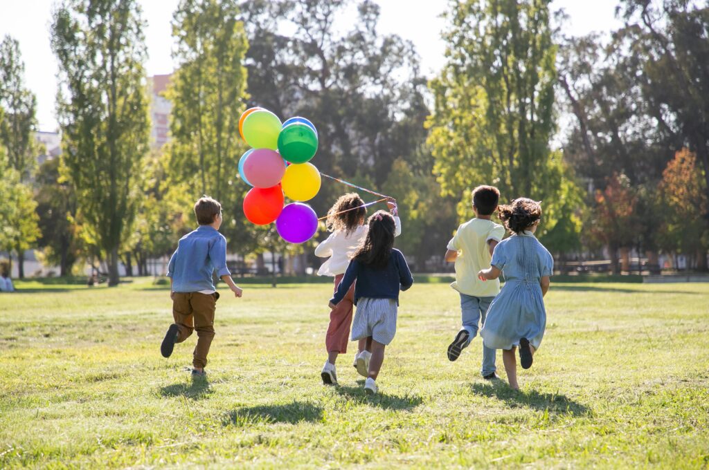 Kindergeburtstag in Hamburg: Kinder rennen über Wiese mit Luftballons