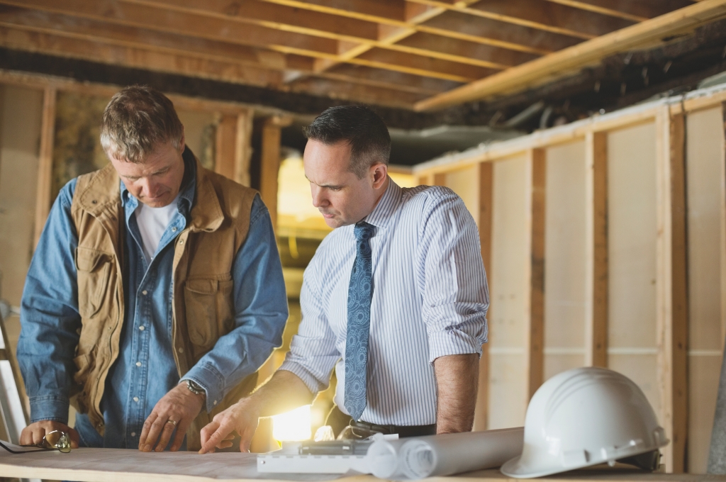 ein Architekt und ein Handwerker diskutieren über Baupläne