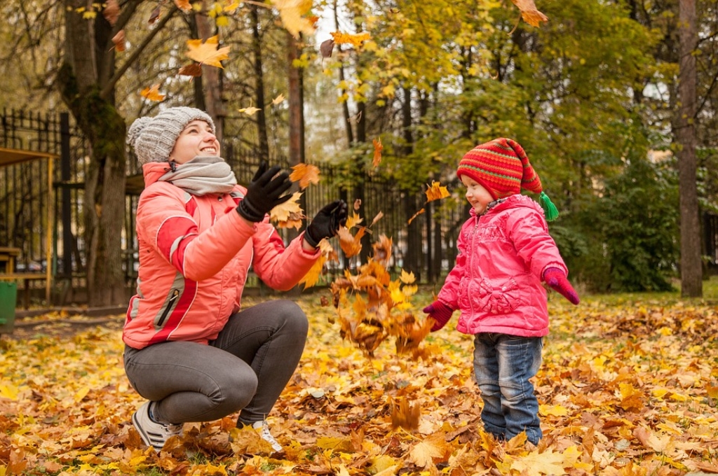 Hamburg im Oktober: Junge Frau und Kind spielen im Herbstlaub