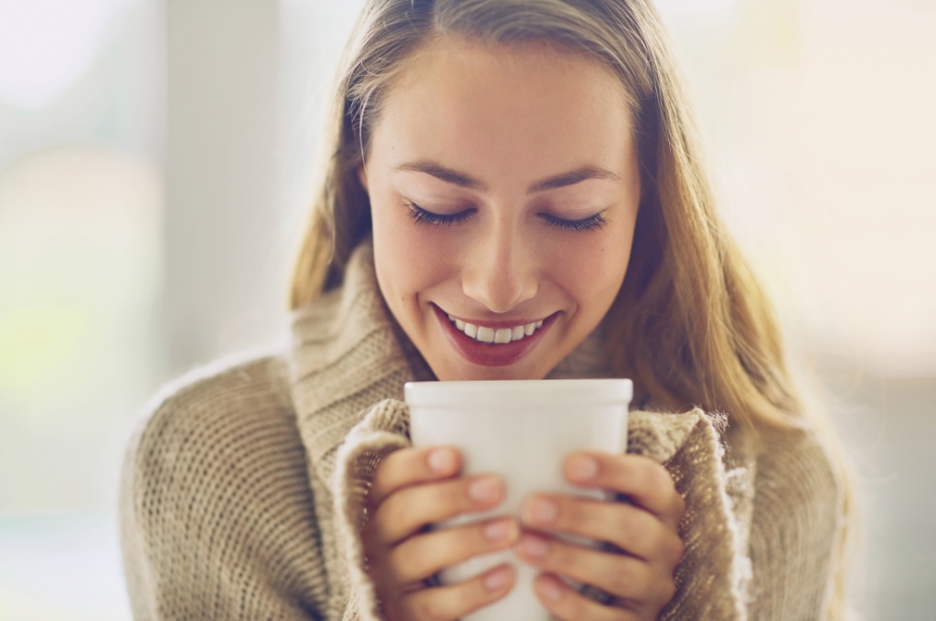 Optimale Raumtemperatur: Frau in Pulli hält eine Tasse in ihren Händen