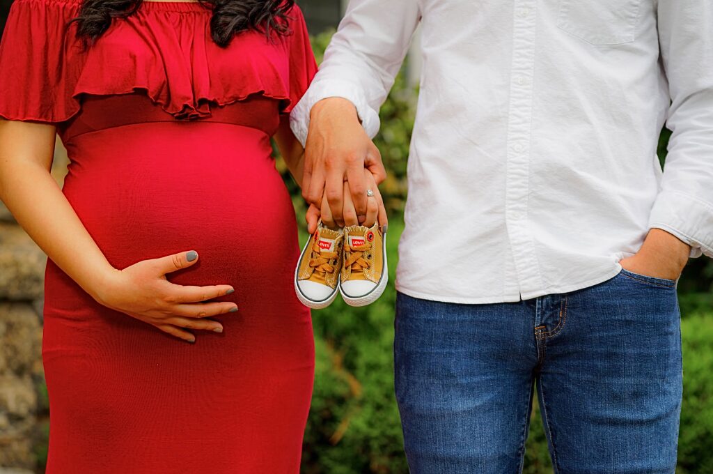 Mutterschaftsgeld berechnen, Schwangere und Partner halten Babyschuhe in die Kamera